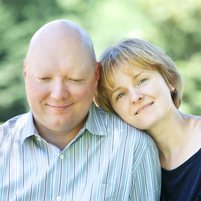 Couple leaning against each other smiling.